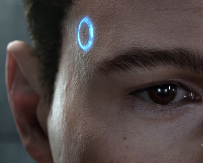 a screenshot of the game Detroit Become Human that shows an android's eye, with a glowing blue circle by their temple