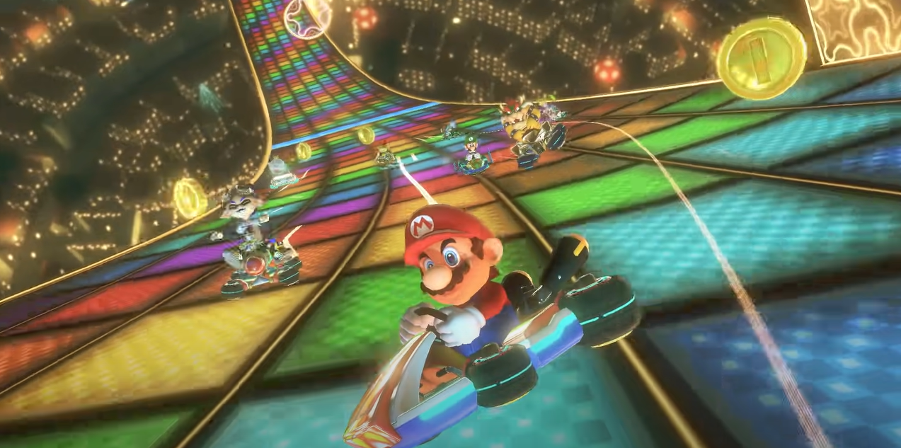 A screenshot of the game depicting mario in a kart racing on a rainbow road